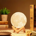 3D Moon Lamp with realistic lunar texture glowing warmly on a wooden stand.